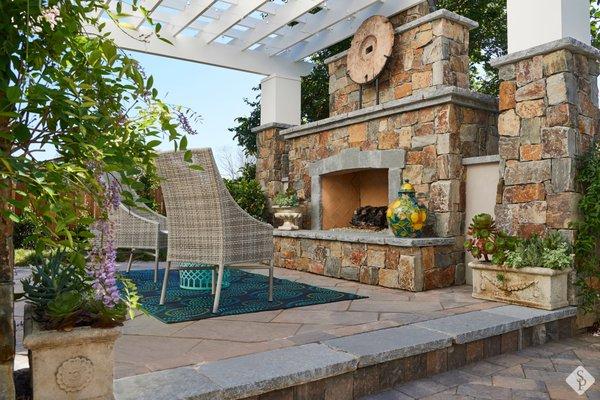 Custom outdoor fireplace design on an elevated paver patio.