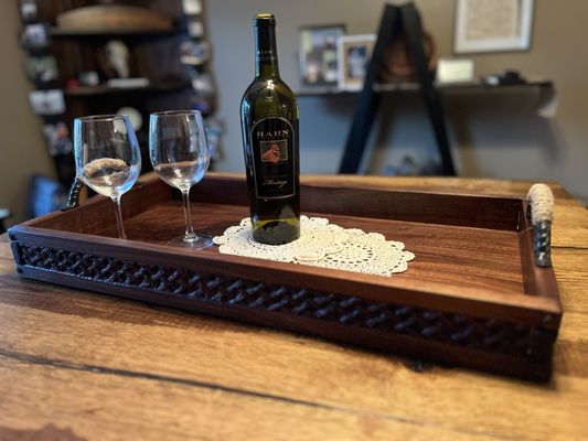 This is a walnut serving tray with artisan handles and hand carved basket weave around the sides