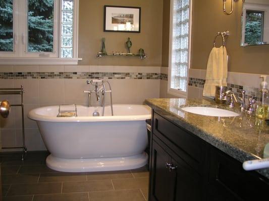 Warm and rich updated master bath with pedestal tub and walk in shower