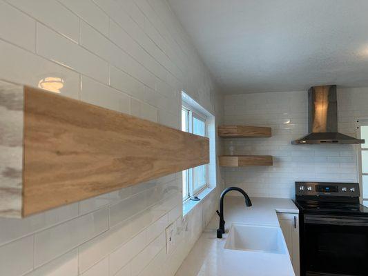 Sleek kitchen remodel. Premium wood floating shelves, subway tile up to ceiling and modern appliances. Culinary luxury reimagined