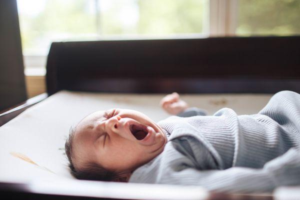 A newborn baby yawns at an in-home newborn session