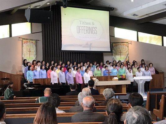 Women's club sing in front of congregation.