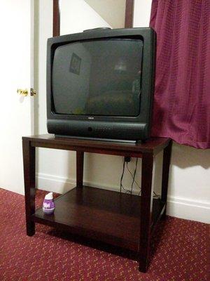 Modern tube television with Renuzit room deodorizer on the bottom shelf.