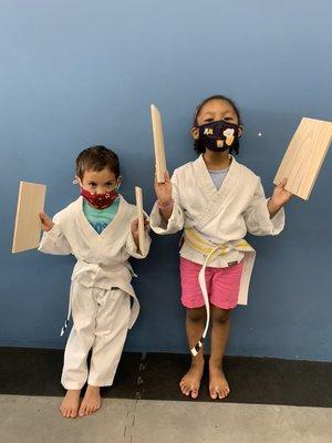 Two students showing off the boards they just broke.