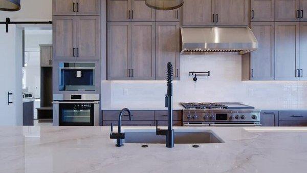 Modern wood kitchen cabinets paired with quartzite countertops and full backsplash. 
 Beautiful black kitchen faucet to tie it together.