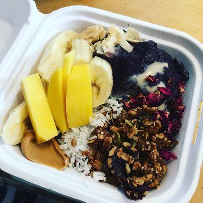 Acai blueberry with granola, mango, banana, coconut, peanut butter, dates and dried rose.