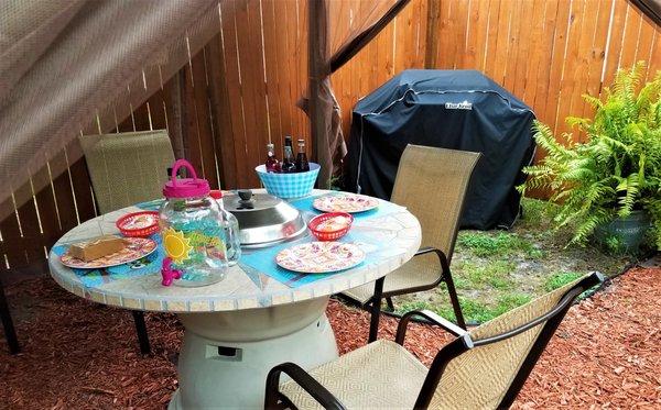 The outdoor entertainment area features a table, grill and fire pit