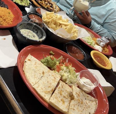 A full table of good food. Piña Coladas, quesadillas, guacamole, rice, all the good stuff.