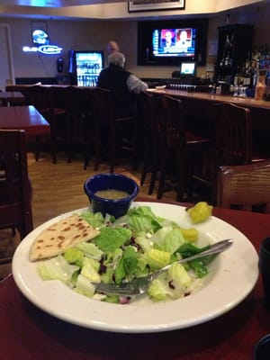 Half eaten Greek salad with bar background.