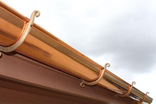 Copper half-round gutters with custom hangers.