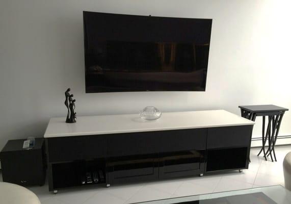 Black lacquer entertainment unit with white marble top and glass doors.