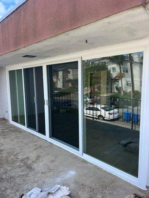 Large Vinyl Patio Door with four panels with double glass and screens. Look before and after installation.