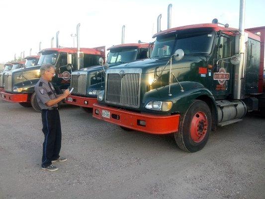 Officer documenting trucks and loads on yard.