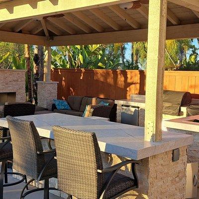 New outdoor kitchen, bar and ventless fireplace under open beam hip patio cover. Custom Stone and granite counters