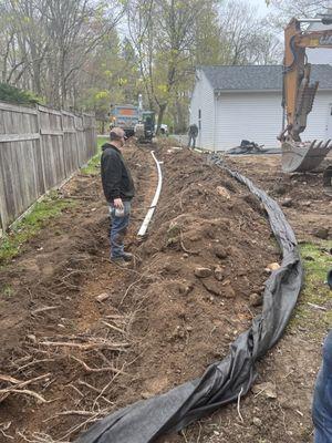 Yard grading, stump removal, drainage/underground rain leaders, prep for future patio area, re-grade yard, R-4 stone erosion control.