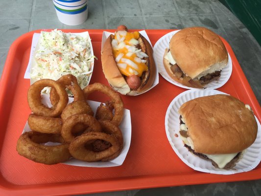 Burgers with grilled onions, a chili cheese dog, slaw, and onion rings.