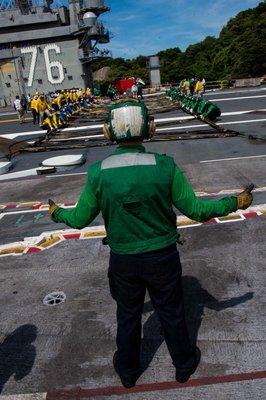 Sailors conduct drills on the flight deck of an aircraft carrier.