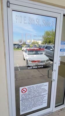 See the address and hours painted on the door. See the reflection of the Weslaco Knapp Medical Center.