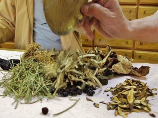 Shop assistant assembling together my prescription of Chinese herbs.