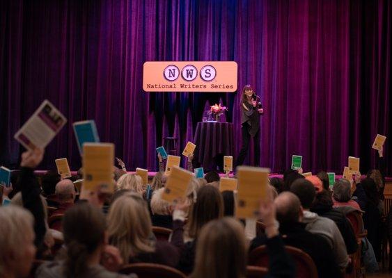 Author Jen Sincero asks the sold-out crowd to hold up books of hers they brought with them.