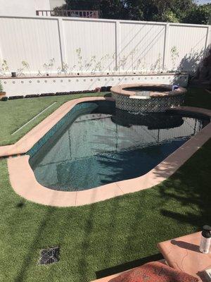 Same small pool and spa  in a small yard Poured in place cement coping  With synthetic grass surrounding this yard