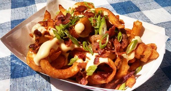 Loaded Fries- seasoned fries topped with queso cheese sauce, crispy bacon crumbles, and green onion