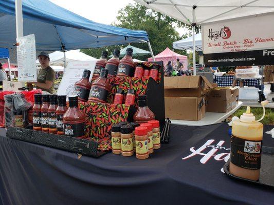 A display of Amazing Hazel's flavorful hot sauces and glaze. Displayed in bottles on a table.