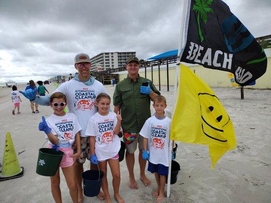 Beach Squad Beach Cleanup volunteers next to the Beach Squad Smiley flag in Daytona Beach, FL - Volusia County