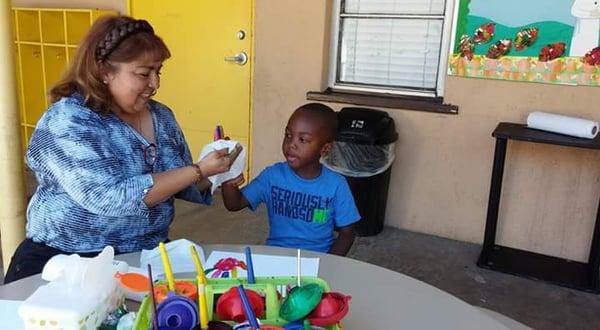 One of our teachers paints the hand of her student to create a memorable handprint.