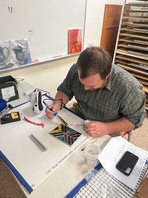 A student hard at work soldering in our Stained Glass studio