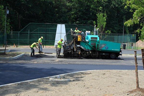 Smooth Paving employees wearing safety gear working with a pavement machine on a pavement project.