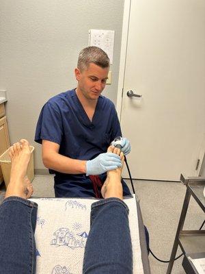 Dr. Anderson performing shockwave therapy to my foot. Not painful at all.