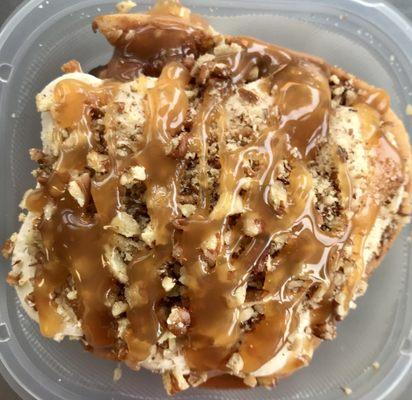 A cinnamon roll with Maple cream cheese frosting pecans and caramel drizzle.