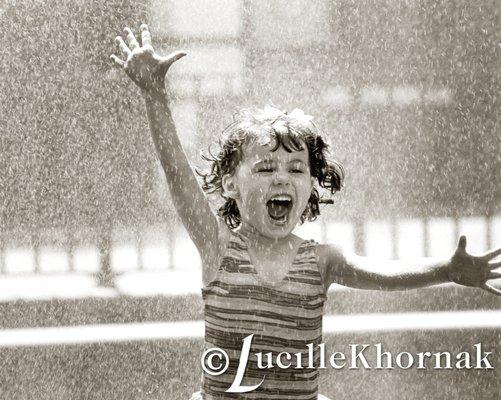 Kids love water.  Sprinklers or a hose can make for a fun photography session as you can see the joy on this child's face.