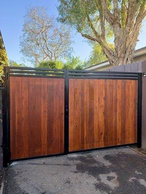 Swinging gate with powder coated steel frame and interior vertical redwood planks.