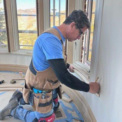 Professional carpenter meticulously installing window casing in a luxurious residential setting. The image captures a skilled woodworker.