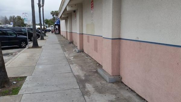 Trash and liquor bottles all along the sidewalk and curbside.