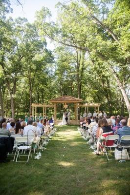 Outdoor wedding ceremonies at wedding pergola with church pew seating.