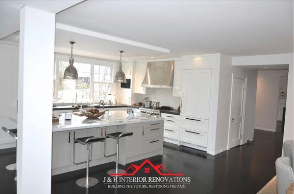 Open concept kitchen white shaker cabinetry 
 , massive island with fridge panels.