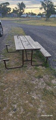 Picnic table is missing an entire seat, leaving bare metal exposed.