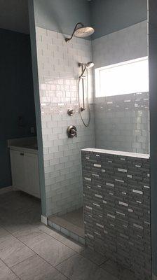 Glass tile shower with stainless steal accents.