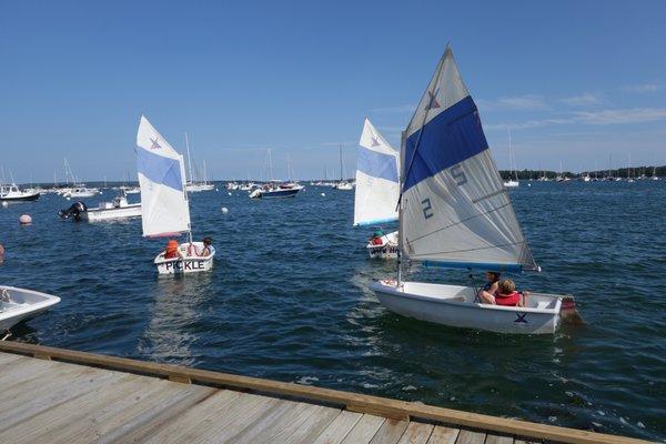 Minnows sailing camp, two kids in each pram sailing around near the dock.