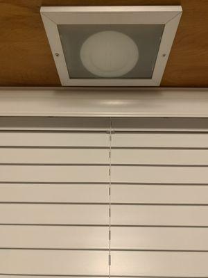 Attached to underside of cabinet above window over light fixture.