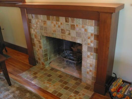 Uncovered vintage tile fireplace beneath false brick veneer façade. Damaged tiles painted and sealed to match cleaned ones.