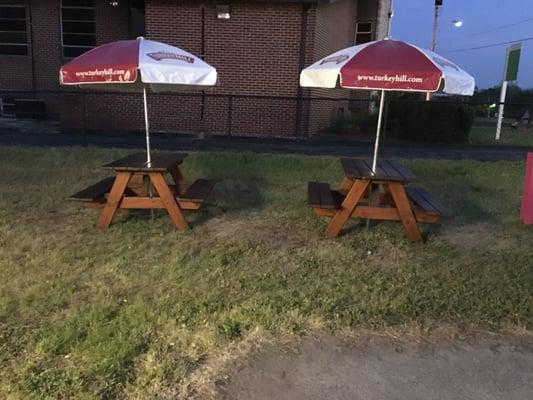 Two picnic benches set up with umbrellas, to the right of the snowball stand.