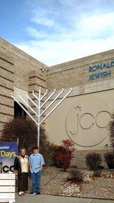 My grandson and I posing for a photo under the Hanukkah Menorah on the 1st Night of Chanukah 2022.