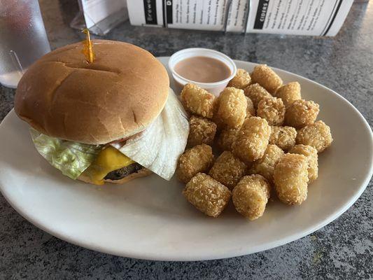 Hamburger with added cheese and tots side.