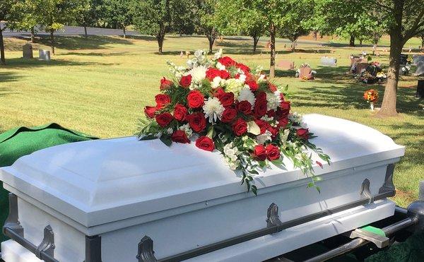 Casket spray with red roses.