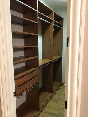 Narrow walk in closet with scoop drawers and slide out pants rack.