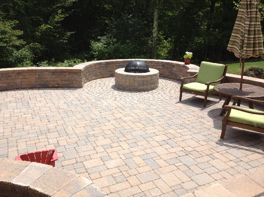 A outdoor living space with a fire pit & seating walls.